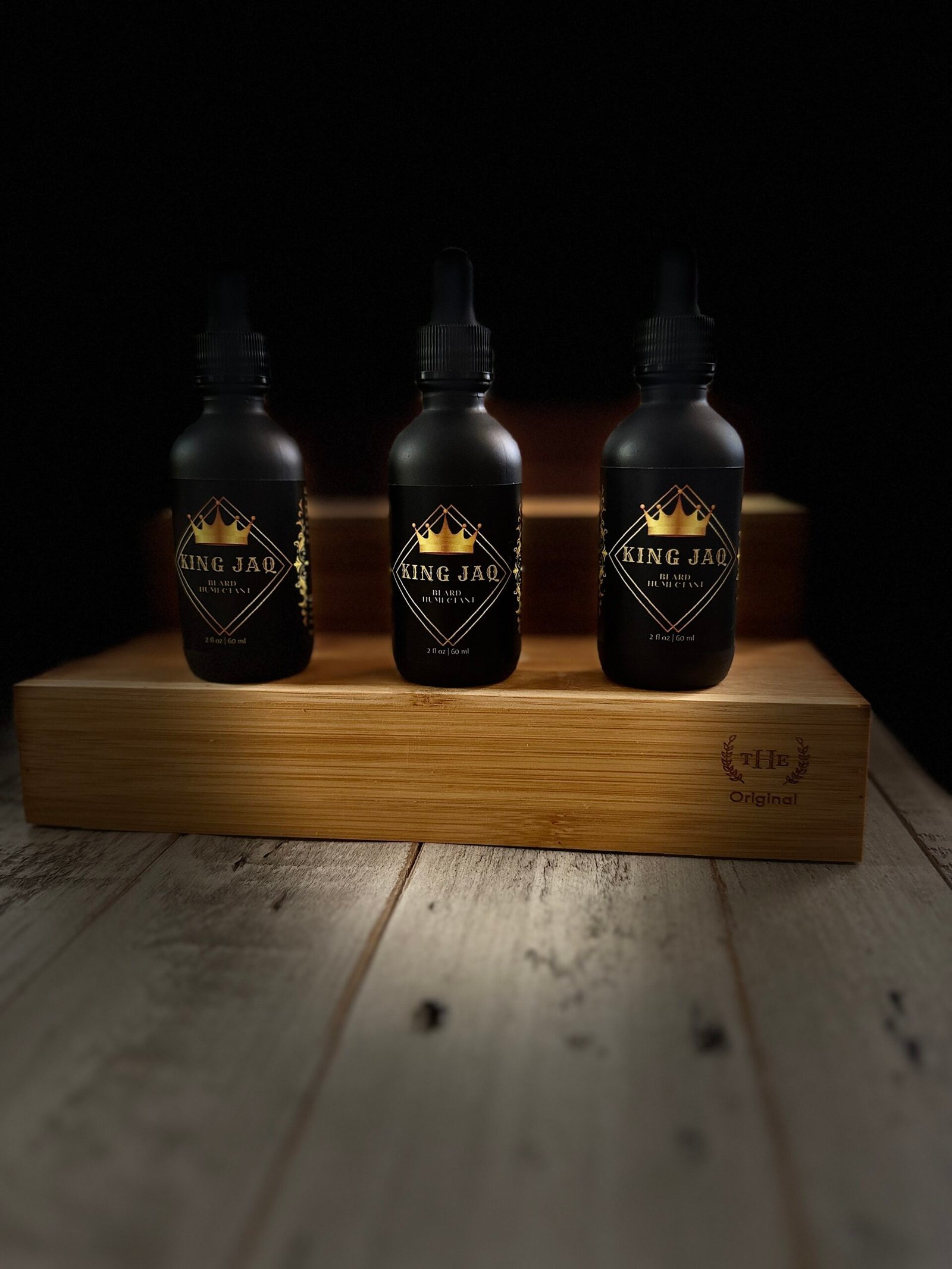 King JAQ beard oil bottles displayed in a luxury grooming setup with warm lighting