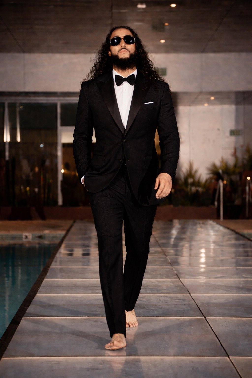 Model walking in a tailored black suit by JAQ LAWRENCE during a luxury fashion presentation